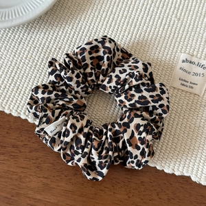 Close-up of leopard print scrunchie with handmade woven label on cotton linen fabric