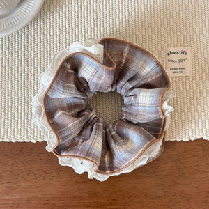 Detailed view of large plaid hair scrunchie with white lace edges and layered texture