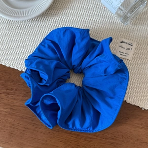 Detailed view of large royal blue ruffled scrunchie with soft fabric texture on a table