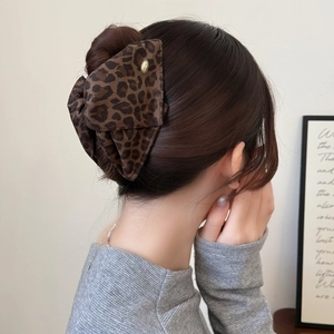 Leopard print bow hair claw clip with gold metal tag on model's hair style