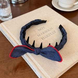 Detail of denim blue headband with red stitching and bow on a vintage book