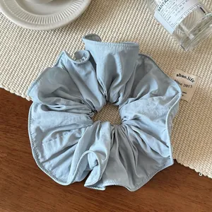 Detailed texture of light blue ruffled fabric scrunchie with neat stitching on soft fabric