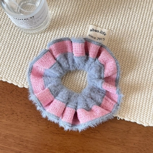 Detailed view of pink and grey striped plush scrunchie with designer brand woven label