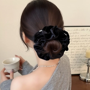 Détail d'un chouchou en velours noir élégant avec perles blanches sur une coiffure en chignon