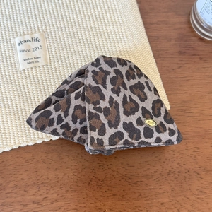 Detail of leopard print fabric hair claw clip with a gold metallic wings logo tag