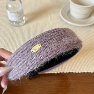 Plush knitted lavender headband with a gold metal bow emblem and fuzzy mohair texture