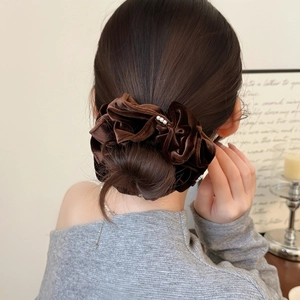 Détail d'un chouchou en velours marron foncé avec trois perles sur un chignon