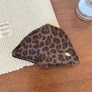 Close-up of leopard print triangle hair claw clip with gold emblem on wooden background