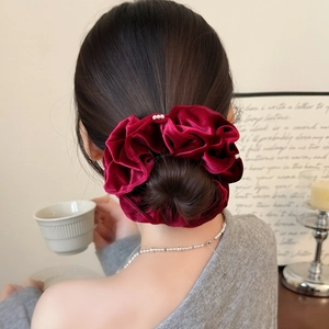 Chouchou élégant en velours bordeaux avec perles pour chignon sur fond de mannequin