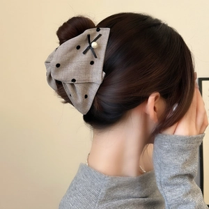Elegant polka dot bow hair claw clip with pearl detail shown on hair for styling