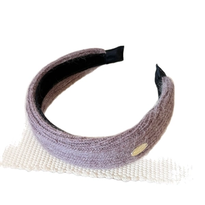 Wide knitted headband in dusty mauve with soft texture and golden metal tag decoration