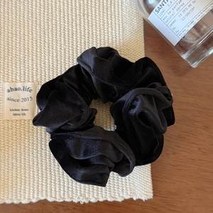 Texture détaillée d'un chouchou en velours noir avec plis doux et élastique élégant