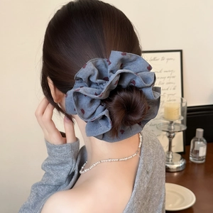 Detail of a large blue hair scrunchie with red heart prints worn on a messy bun hairstyle