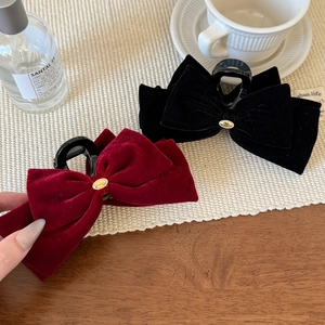 Detail of velvet bow hair claws in black and burgundy with gold metallic accents