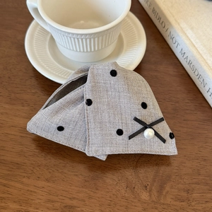 Close-up of grey polka dot fabric hair claw clip with black bow and pearl detail