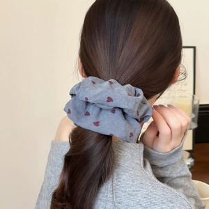 Detail of grey polka dot heart hair scrunchie worn on a high bun in cozy home setting