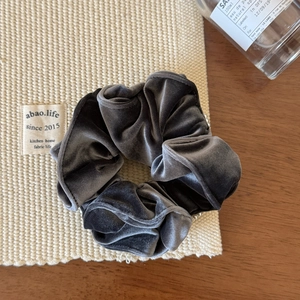 Détail d'un chouchou en velours gris avec perles élégantes sur un support tissé