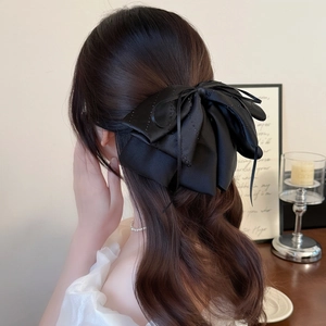 Elegant black satin bow hair clip with rhinestones shown on a model for high volume styling