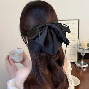 Elegant large black satin layered bow hair clip with ribbons on long wavy hair