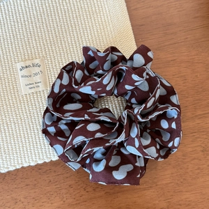 Détail d'un chouchou rouge à cœurs bleus sur bois montrant la texture du tissu