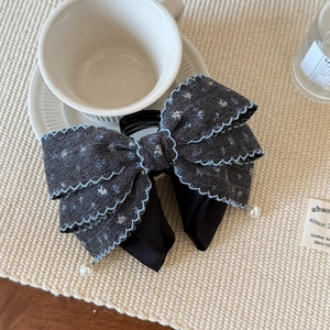 Close-up of a denim bow hair claw with floral patterns and pearl pendants