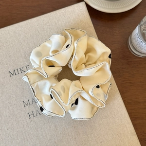 Dettaglio dell'elastico per capelli beige a pois con cuciture nere su un libro