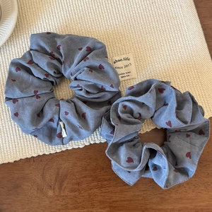 Detailed view of two blue fabric scrunchies with red heart patterns on a woven mat