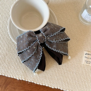 Detailed close-up of a sweet fabric bow hair claw with pearls and embroidery