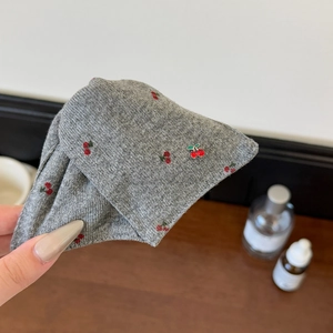 Détail de la pince à cheveux grise tricotée avec broderie cerise et pendentif métal