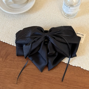 Detail of elegant black satin bow hair clip with sparkling rhinestones and ribbon