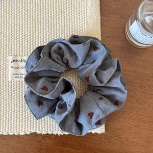 Detail view of dark grey scrunchie with red heart print on soft pleated fabric
