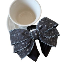 Denim bow hair claw clip with pearl accents and blue embroidery on white background