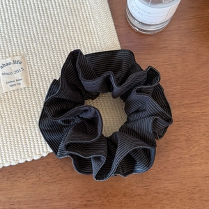 Close-up of black and white striped scrunchie on a wooden desk with soft lighting