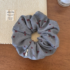Detail of grey fabric scrunchie with red heart patterns on a wooden surface