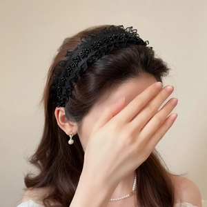 Elegant black lace headband with bead embroidery worn by a model in a side view