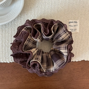Detailed view of autumn brown plaid hair scrunchie with lace trim on a cozy table