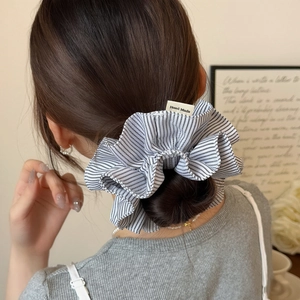 Close-up of blue striped fabric scrunchie with Hand Made label on a low ponytail