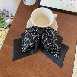 Close-up of elegant black and white paisley bow hair claw clip on a wooden table