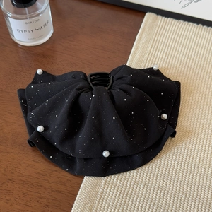 Pince à cheveux nœud noir élégante avec perles et strass sur une table en bois