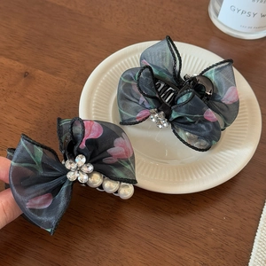 Détail de pinces à cheveux en mesh noir avec imprimés tulipes roses et accents perlés