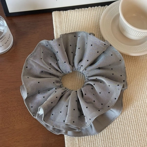 Details des grauen Oversize-Haargummis mit schwarzen Punkten auf elegantem Hintergrund