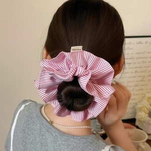Handmade red striped fabric scrunchie accessory worn on hair in a stylish lifestyle setting