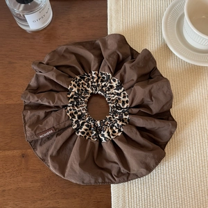 Close-up of leopard print hair scrunchie with FASHION label on wooden table setting