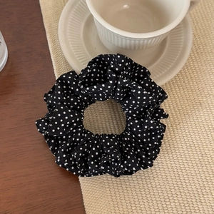 Detail of a black and white polka dot scrunchie on a cozy wooden table background