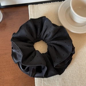 Detailaufnahme von schwarzem gepunktetem Haargummi aus Mesh und Seide auf Holztisch