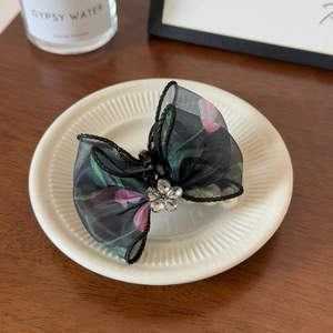 Détail de la pince à cheveux avec nœud en tulle noir, motifs tulipes et perles