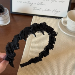 Détail d'un serre-tête en tulle noir ondulé avec texture plissée et dents antidérapantes
