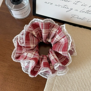Dettaglio dello scrunchie a quadretti rosso e bianco con bordo in pizzo e stelle ricamate