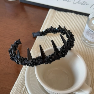 Gothic black beaded headband with punk style spikes on a white ceramic cup display