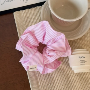 Detailed macro view of pink striped fabric scrunchie with handmade woven label